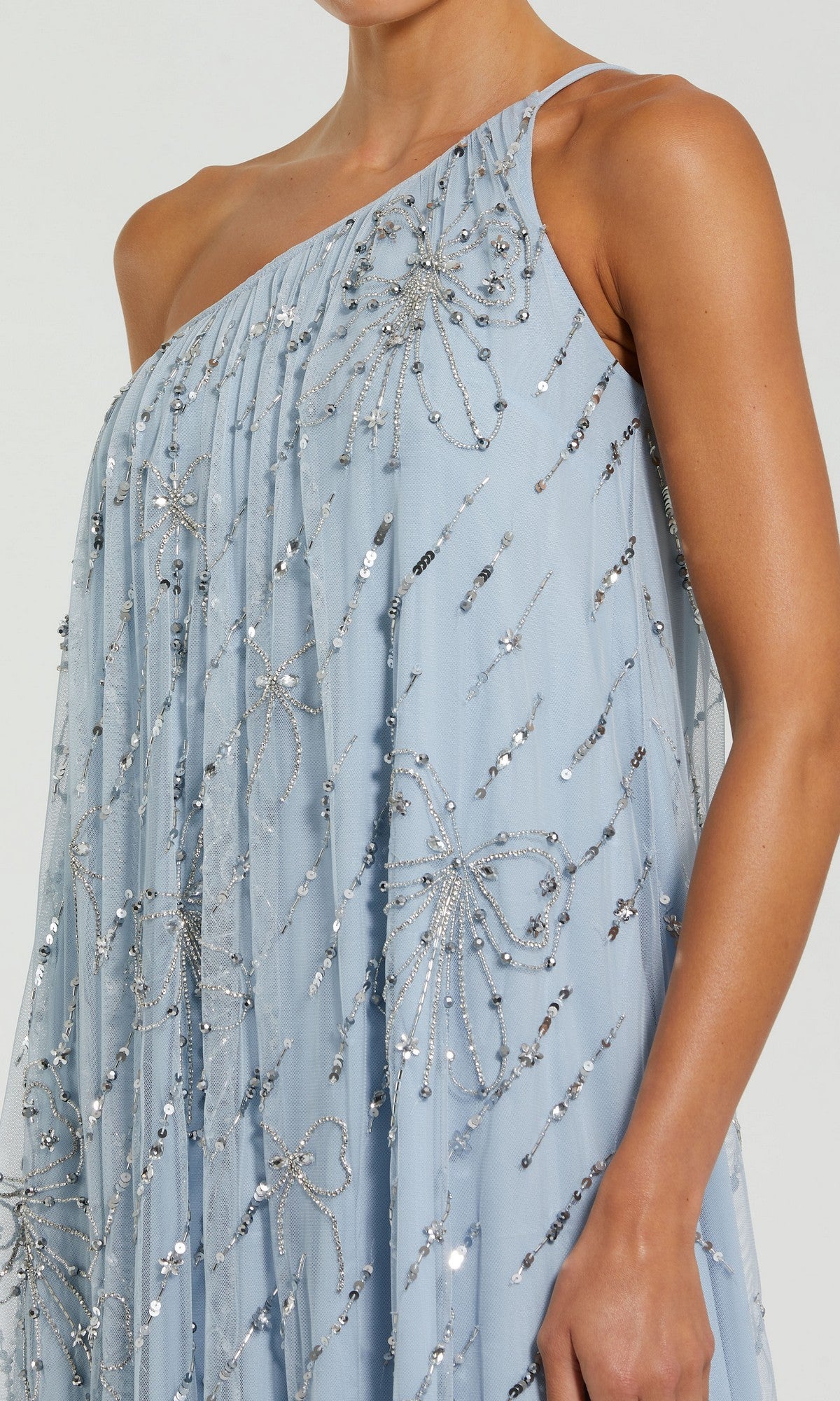 A person wearing the Mac Duggal 9344 Long Formal Dress—a light blue, one-shoulder shift dress with sequin and beaded floral bow embellishments.